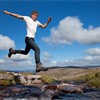 Boy (aged 17) jumping across upland stream, Cairngorms National Park, Scotland, August